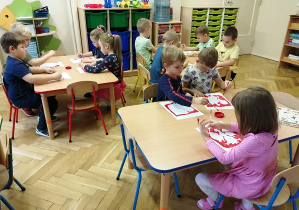 widok z przodu na dzieci siedzące przy stoliku i wykonujące prace